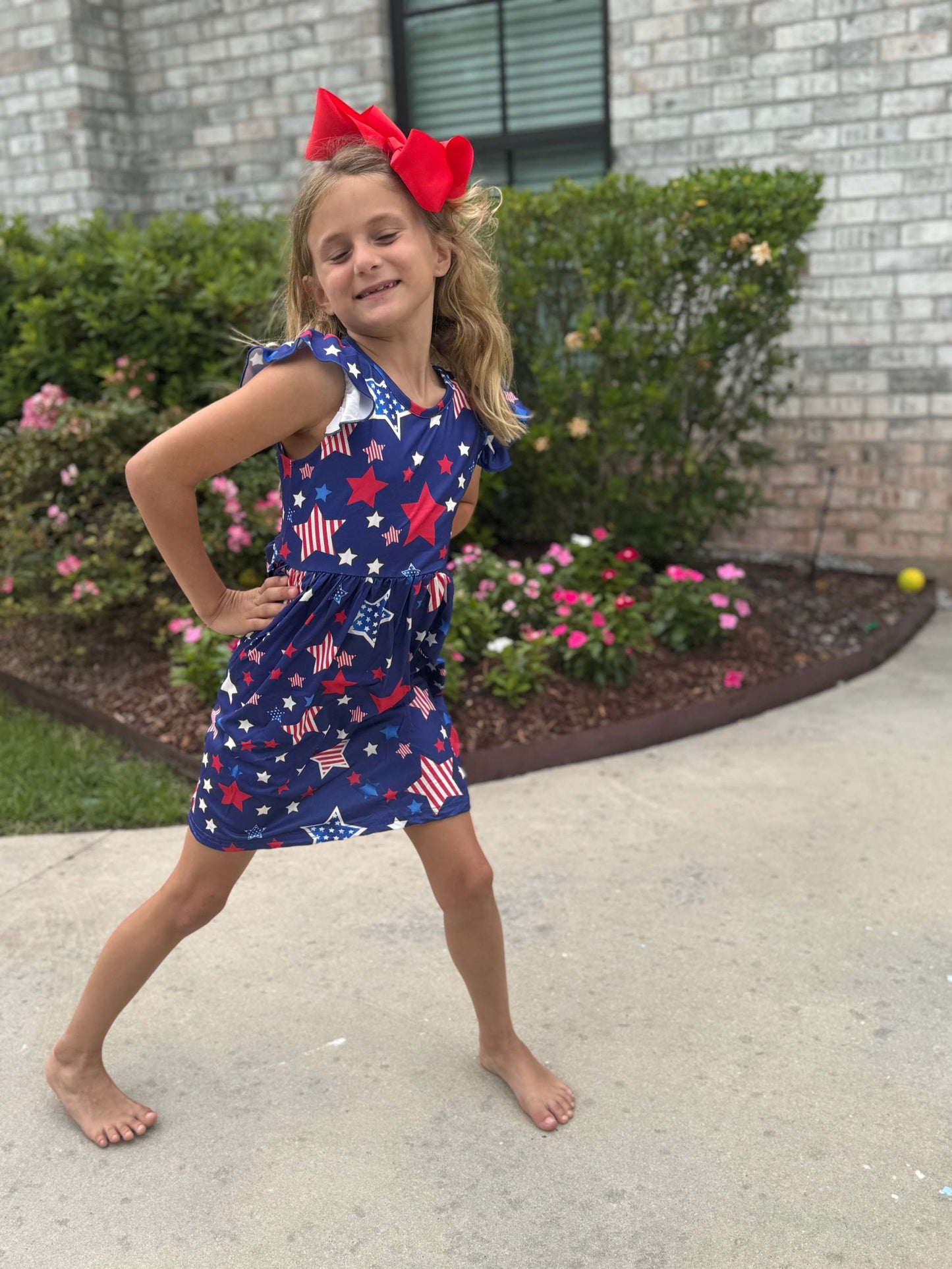 Patriotic girls dress with star graphics and ruffle sleeves.