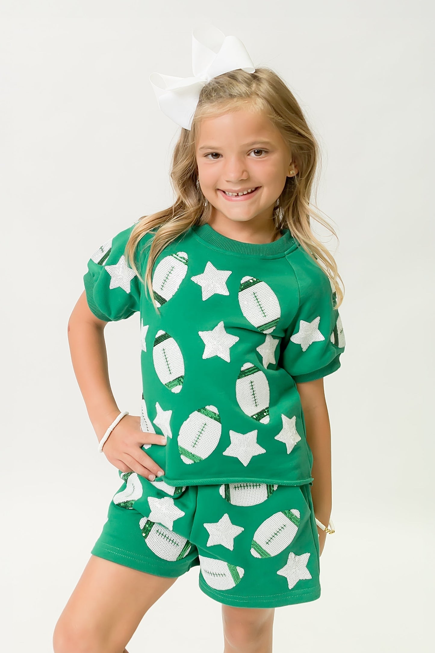 Young girl wearing a green football top and shorts with white football and star patterns