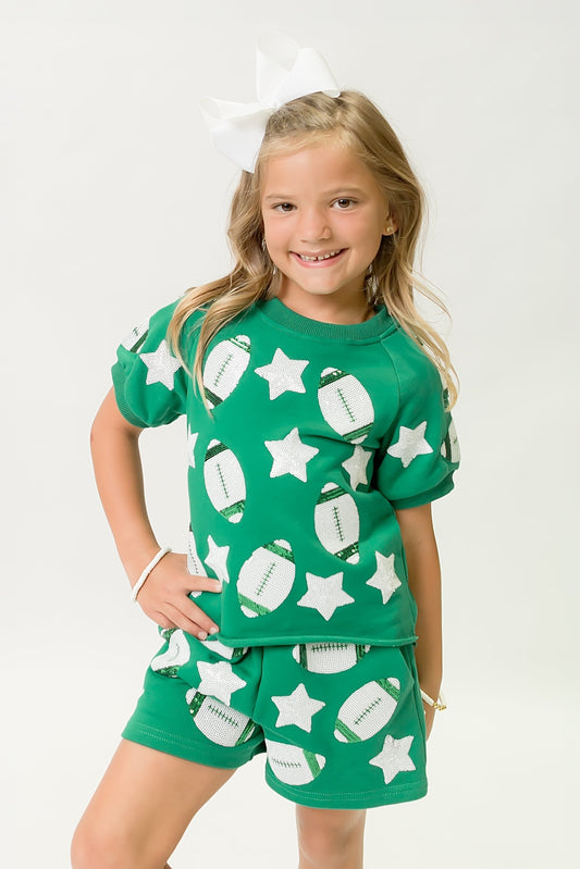 Young girl wearing a green football top and shorts with white football and star patterns