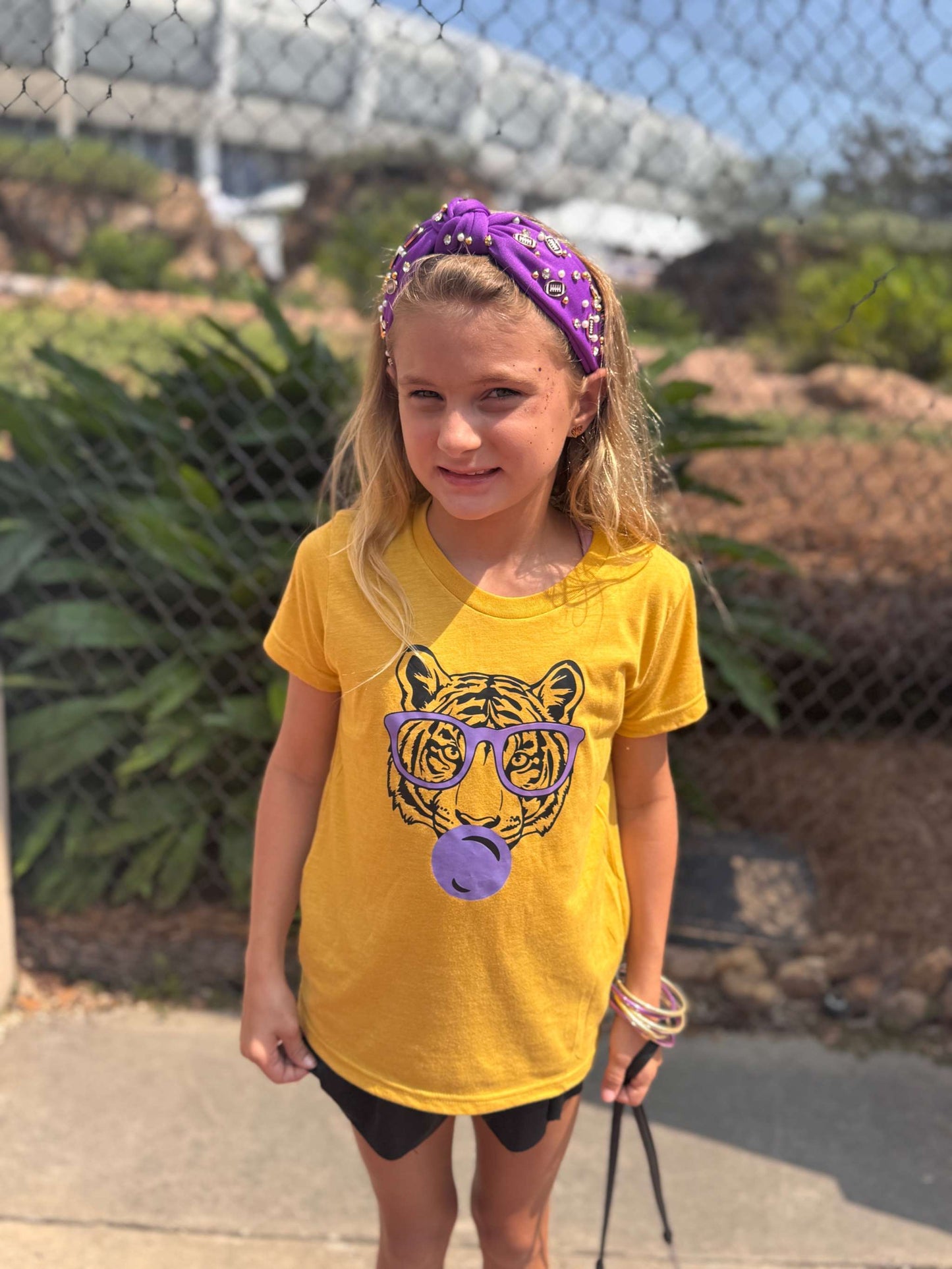 Young girl wearing purple sporty knotted headband with football design outdoors