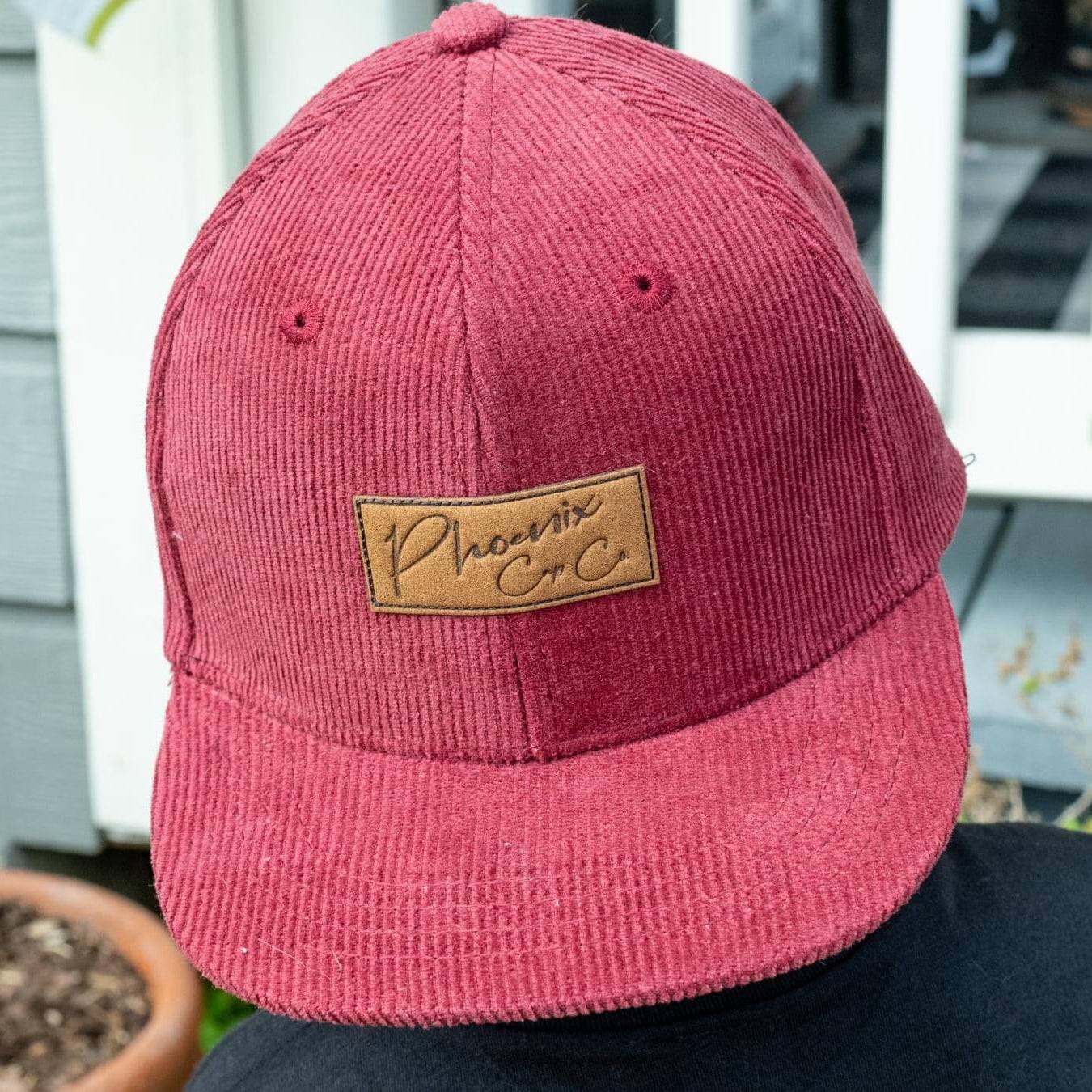 Dusty Rose maroon corduroy hat with leather logo patch and adjustable snap closure.