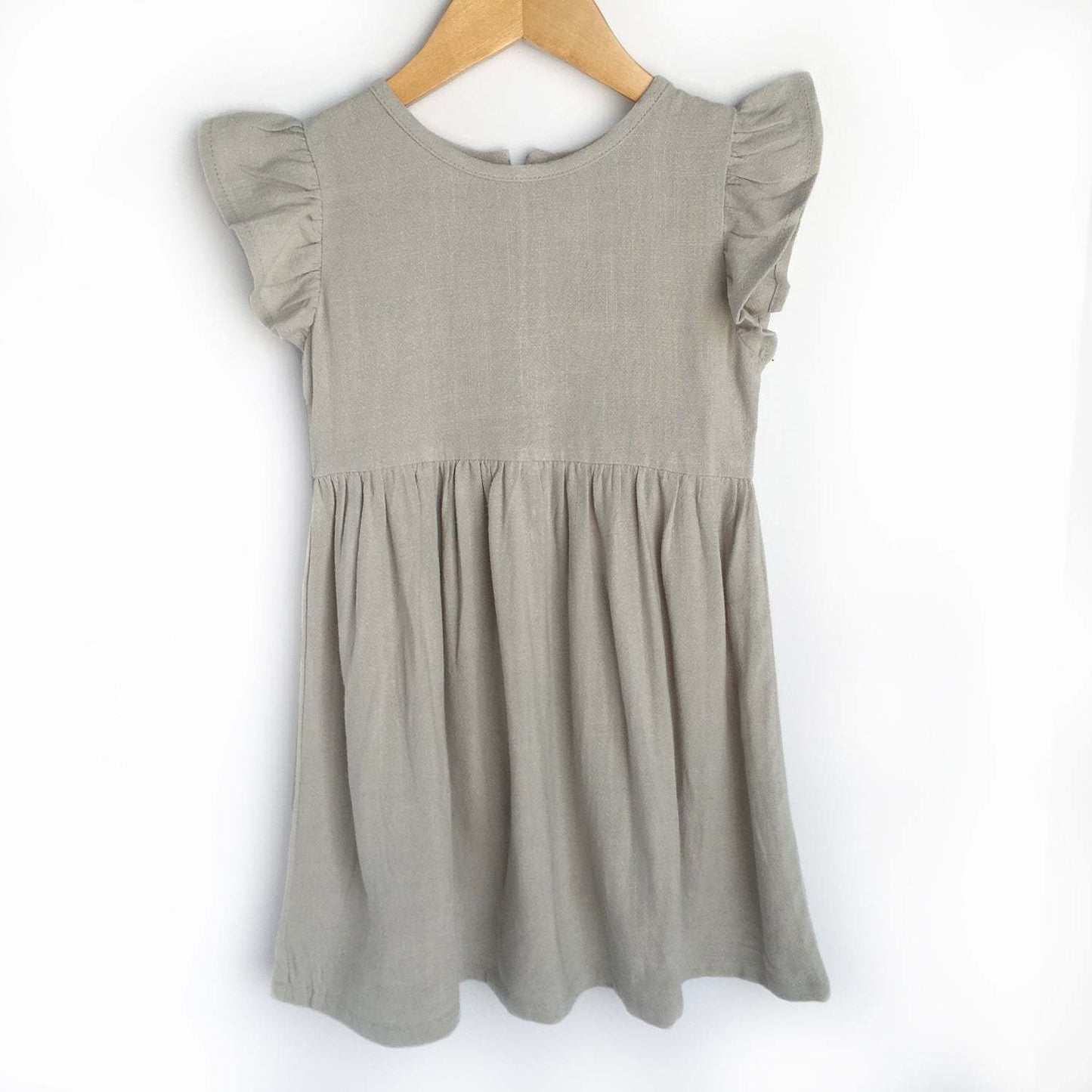 Grey linen dress with flutter sleeves hanging on a wooden hanger.