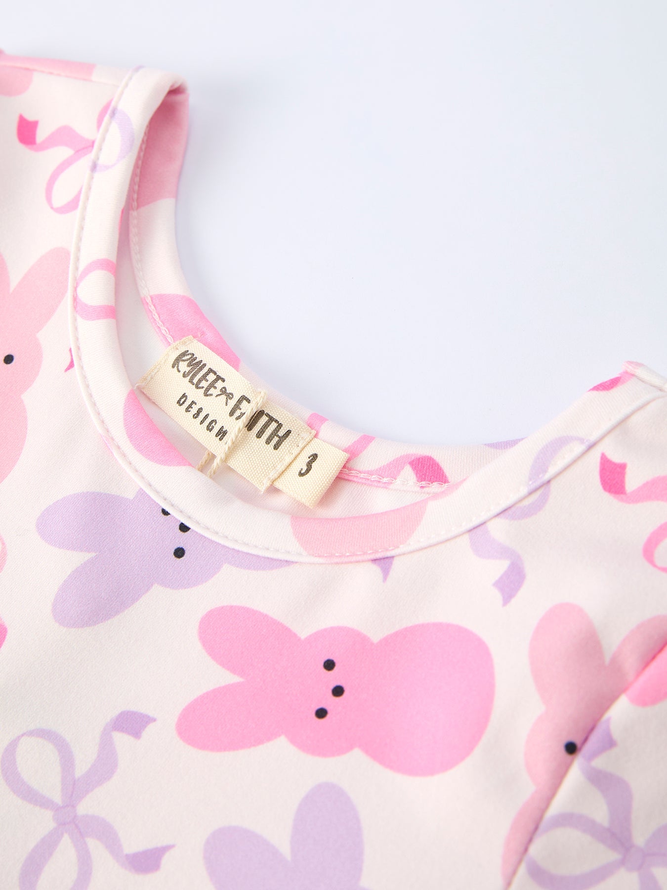 Baby bib with pink and purple floral pattern and 'Kite & Cub' brand tag.