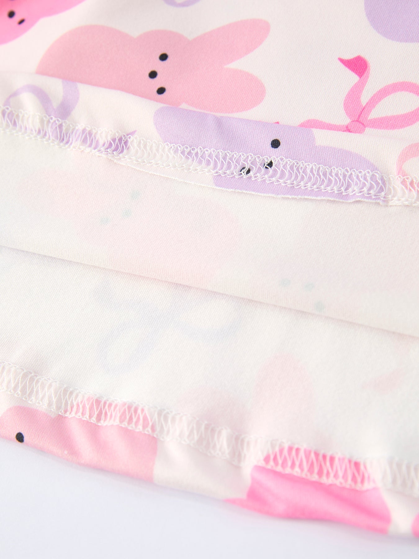 Close-up of a children's outfit with bunny ears and bows on a white background