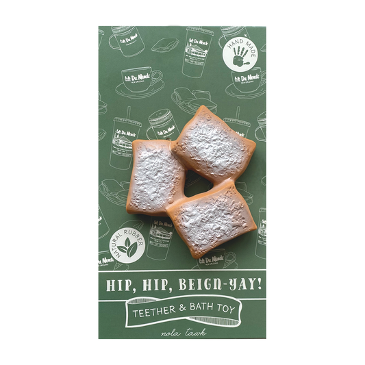 Teether and bath toy packaging with powdered sugar cookies on a green background featuring branding.