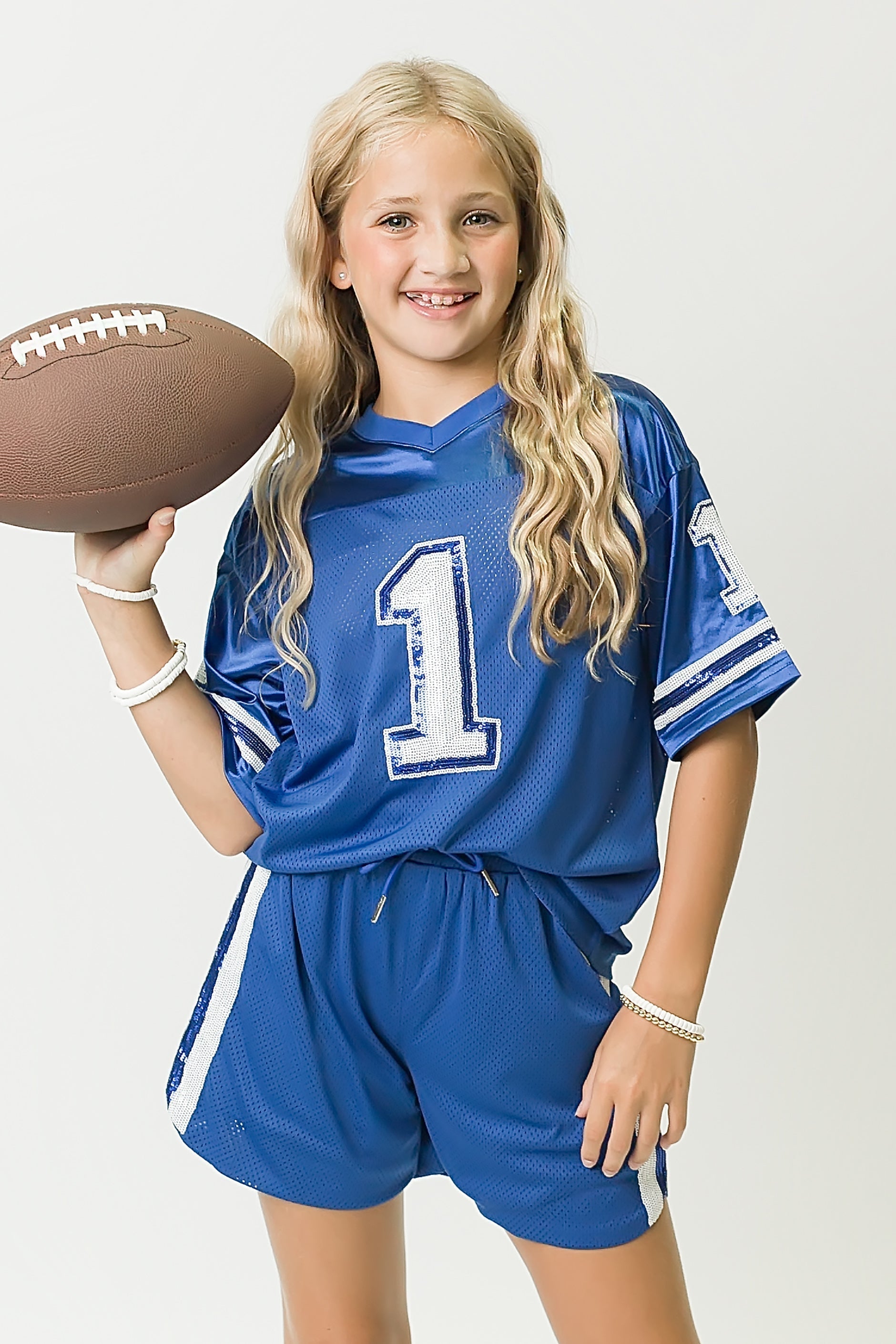 Girl wearing royal blue and white sequin jersey holding football