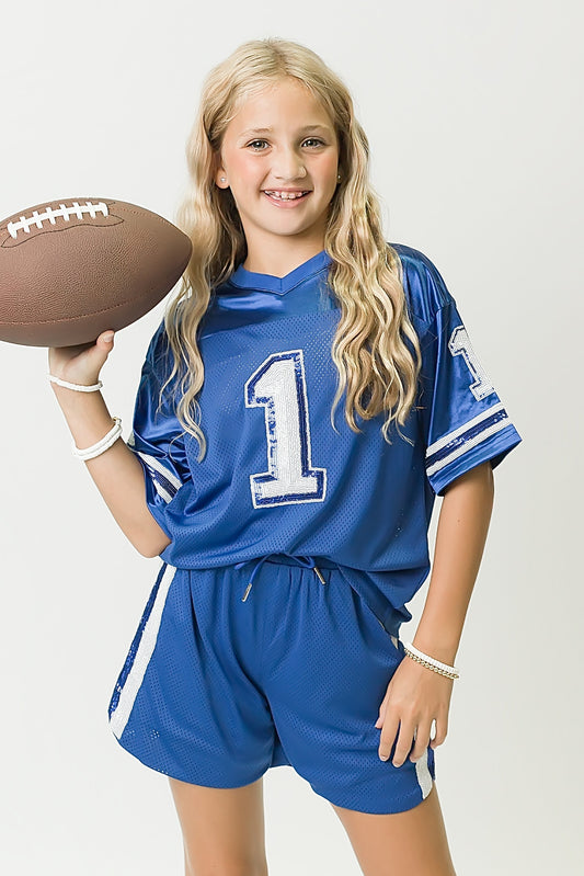 Girl wearing royal blue and white sequin jersey holding football
