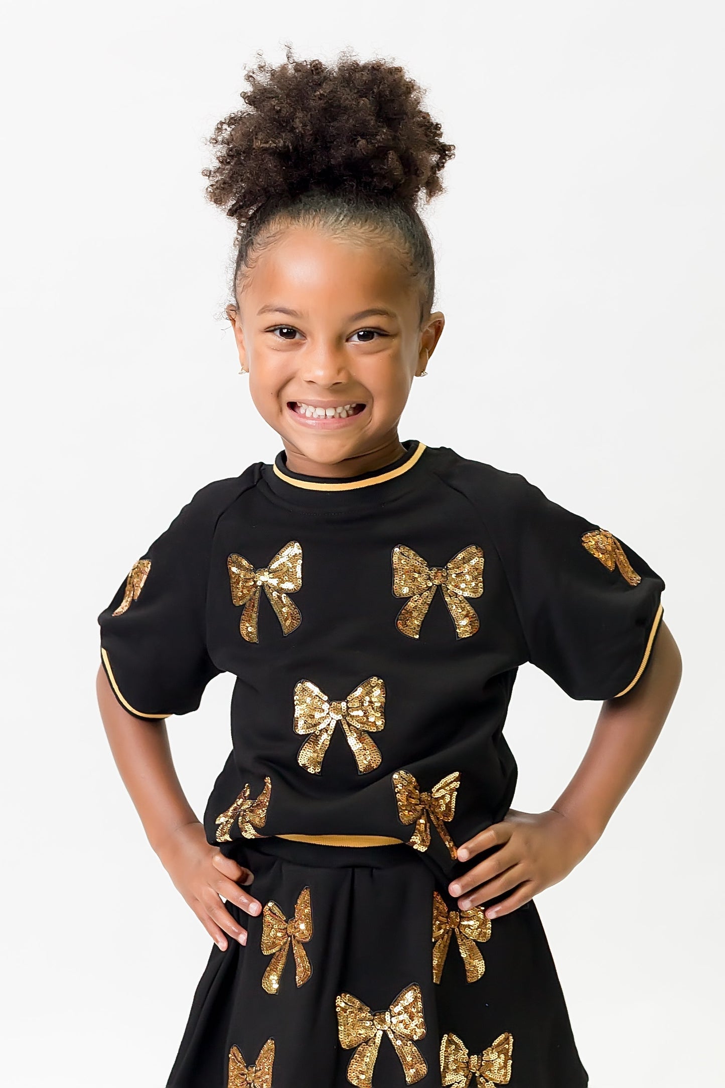 Girl wearing black and gold bows top with sequin bow details