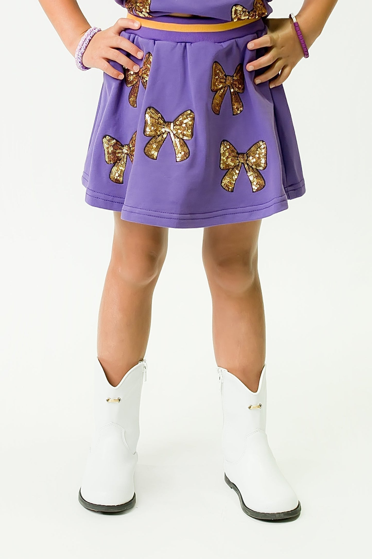 Purple and Gold Bows Skort with glitter bow details and white boots on a child