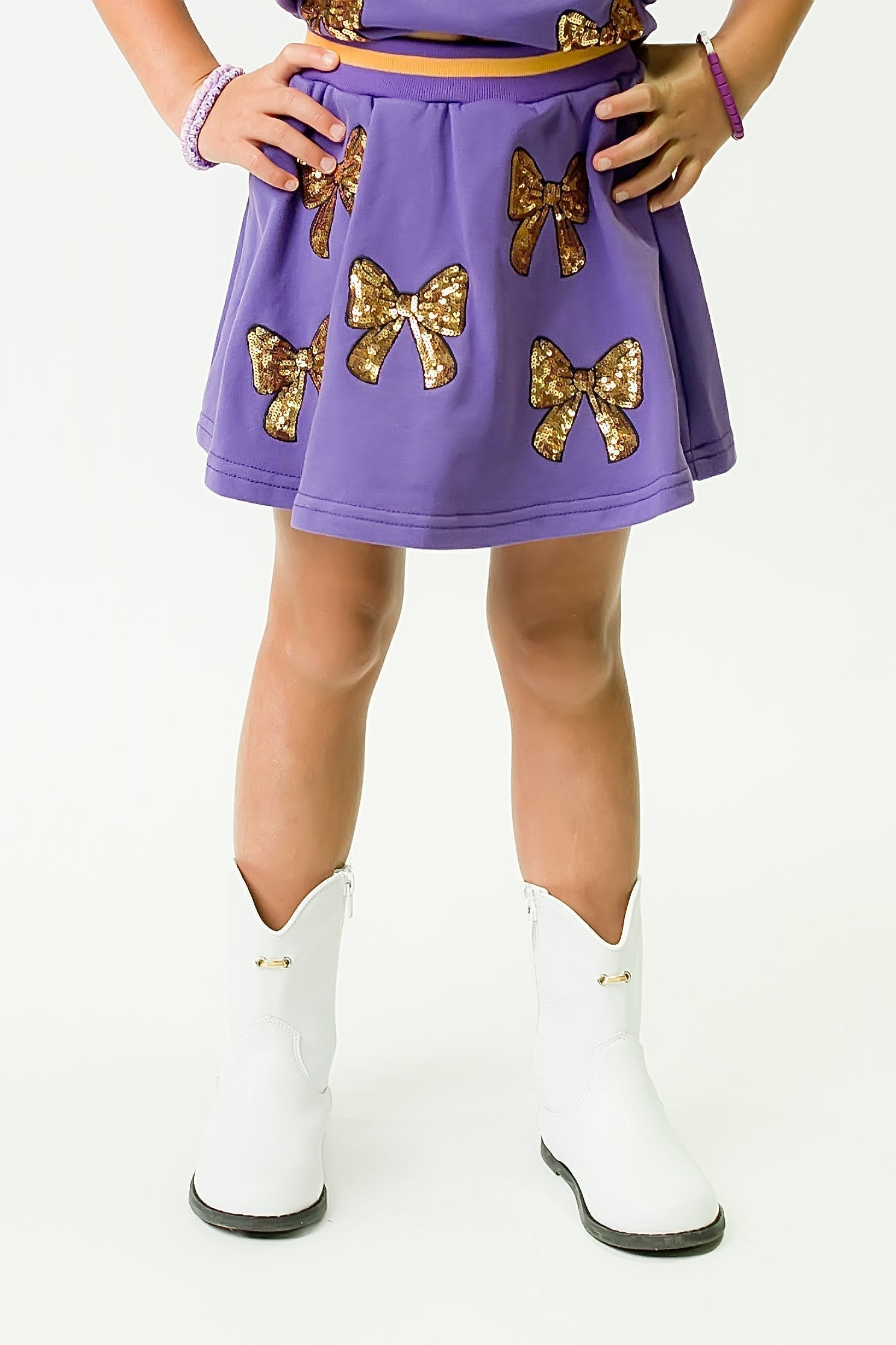 Purple and Gold Bows Skort with glitter bow details and white boots on a child