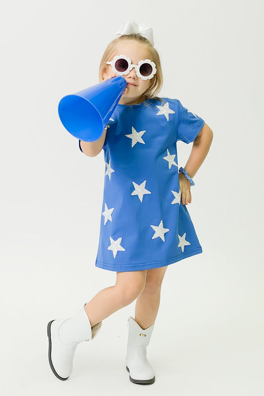 Girl wearing royal blue star dress with white stars and white boots holding blue megaphone