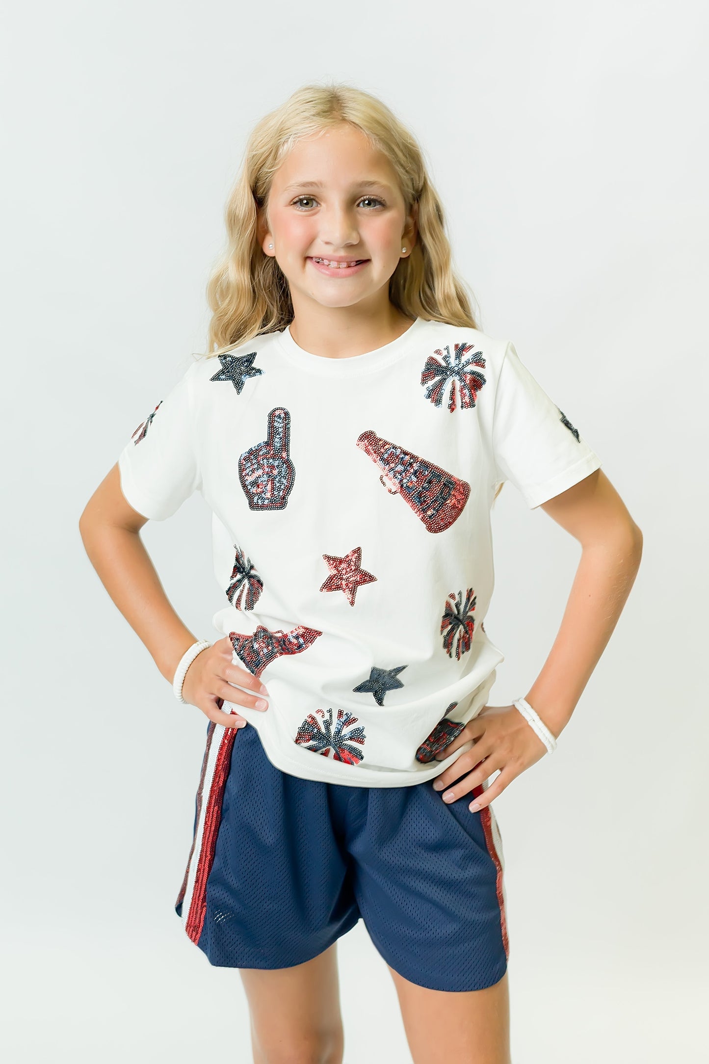 Girl wearing navy and red cheer shirt with cheer-themed graphics and matching shorts