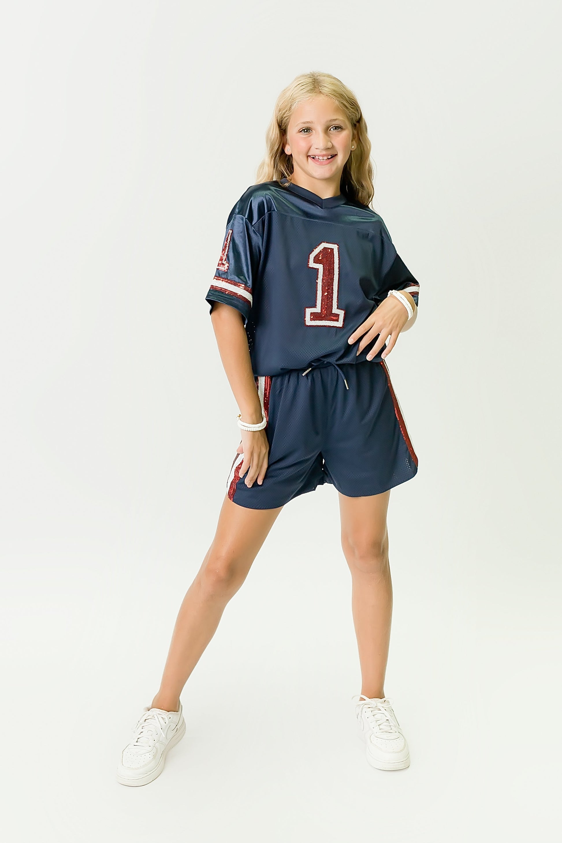 Girl wearing navy blue and red sequin jersey with number 1 and matching shorts standing confidently