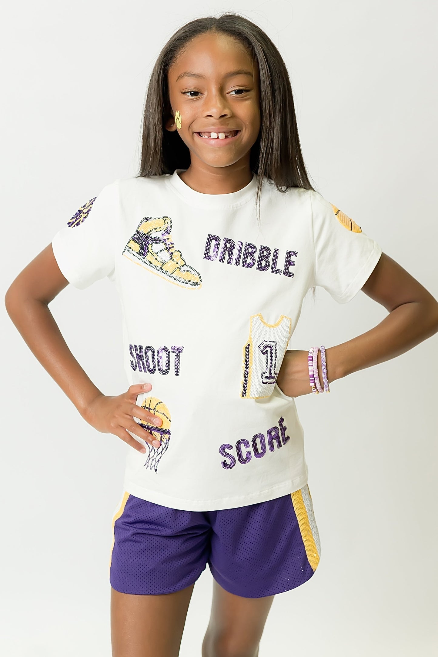 Girl wearing purple and yellow basketball shirt with sporty graphics and matching shorts