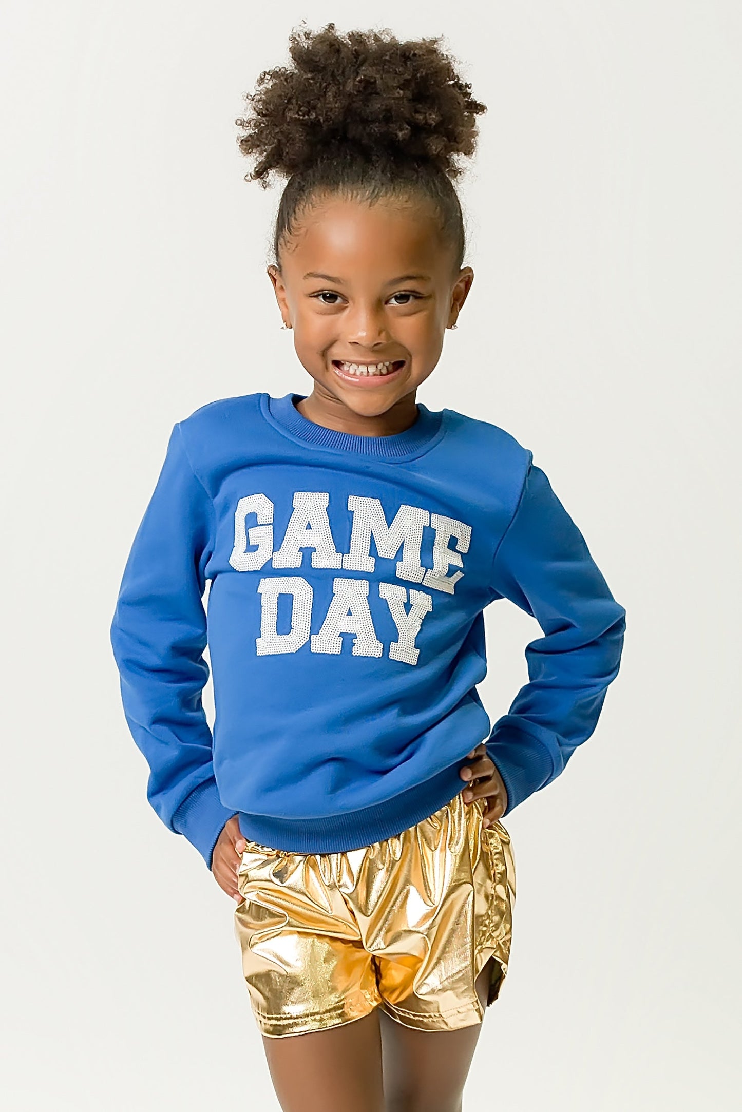 Girl wearing royal blue gameday sweatshirt with "GAME DAY" text and gold shorts