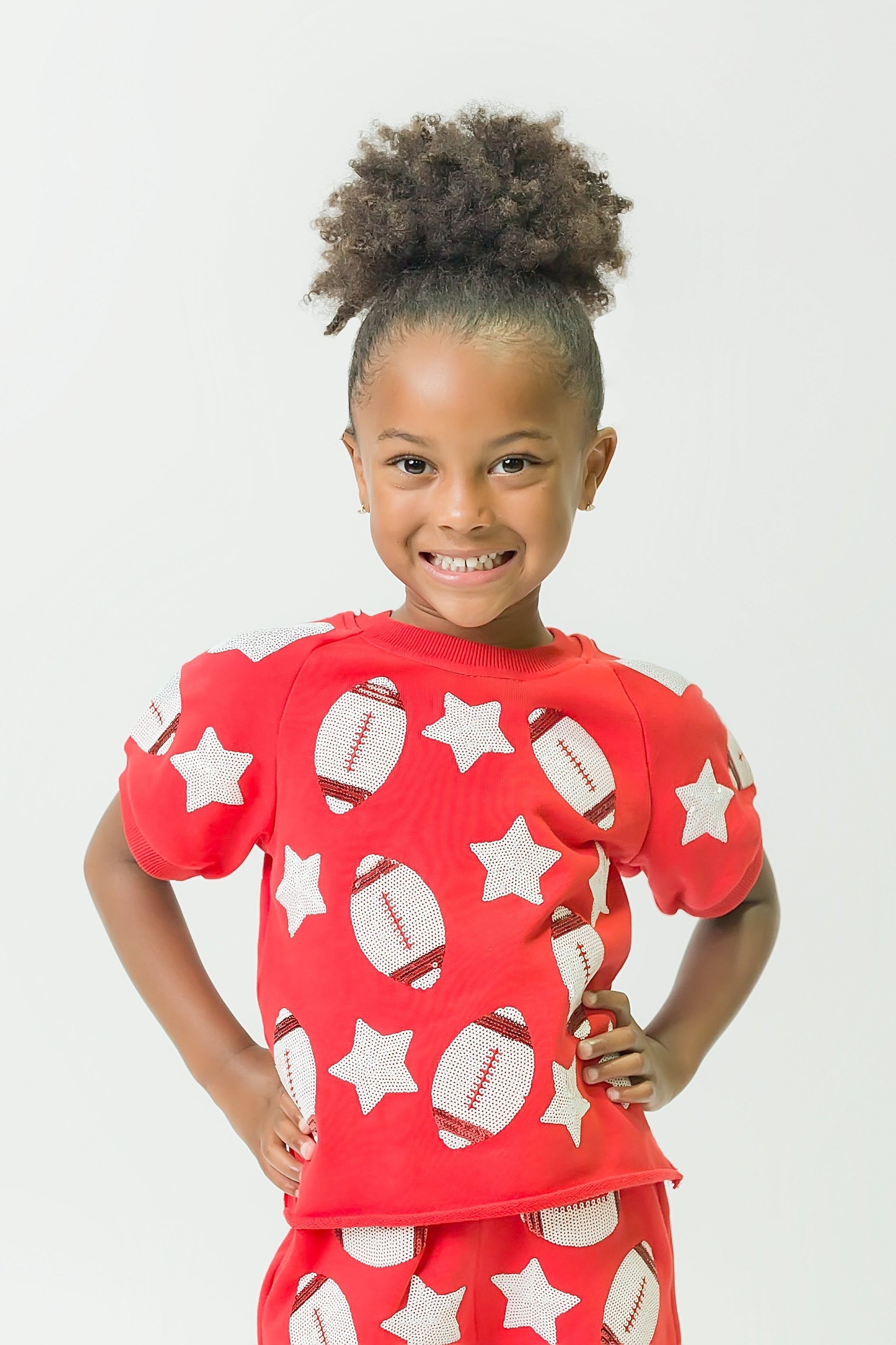 Smiling child wearing red football top with football and star patterns