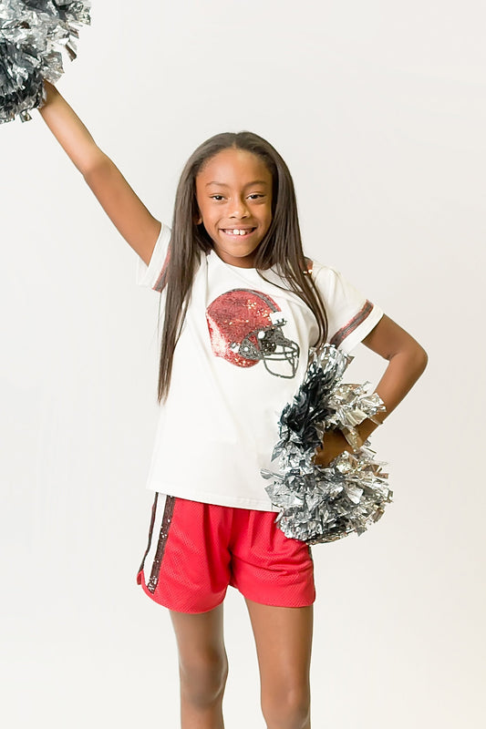 Girl wearing red and black helmet shirt with pom-poms cheering