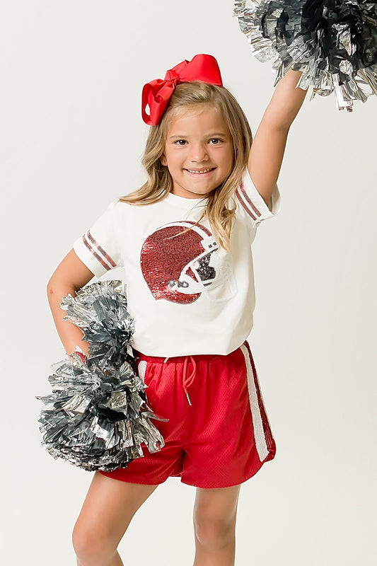 Young girl wearing a Red Helmet Shirt with red sequin football helmet design and matching red shorts cheering with pom-poms