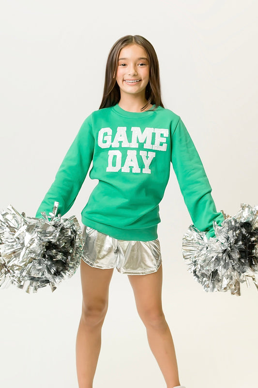 Girl wearing green gameday sweatshirt with "GAME DAY" text and silver pom-poms