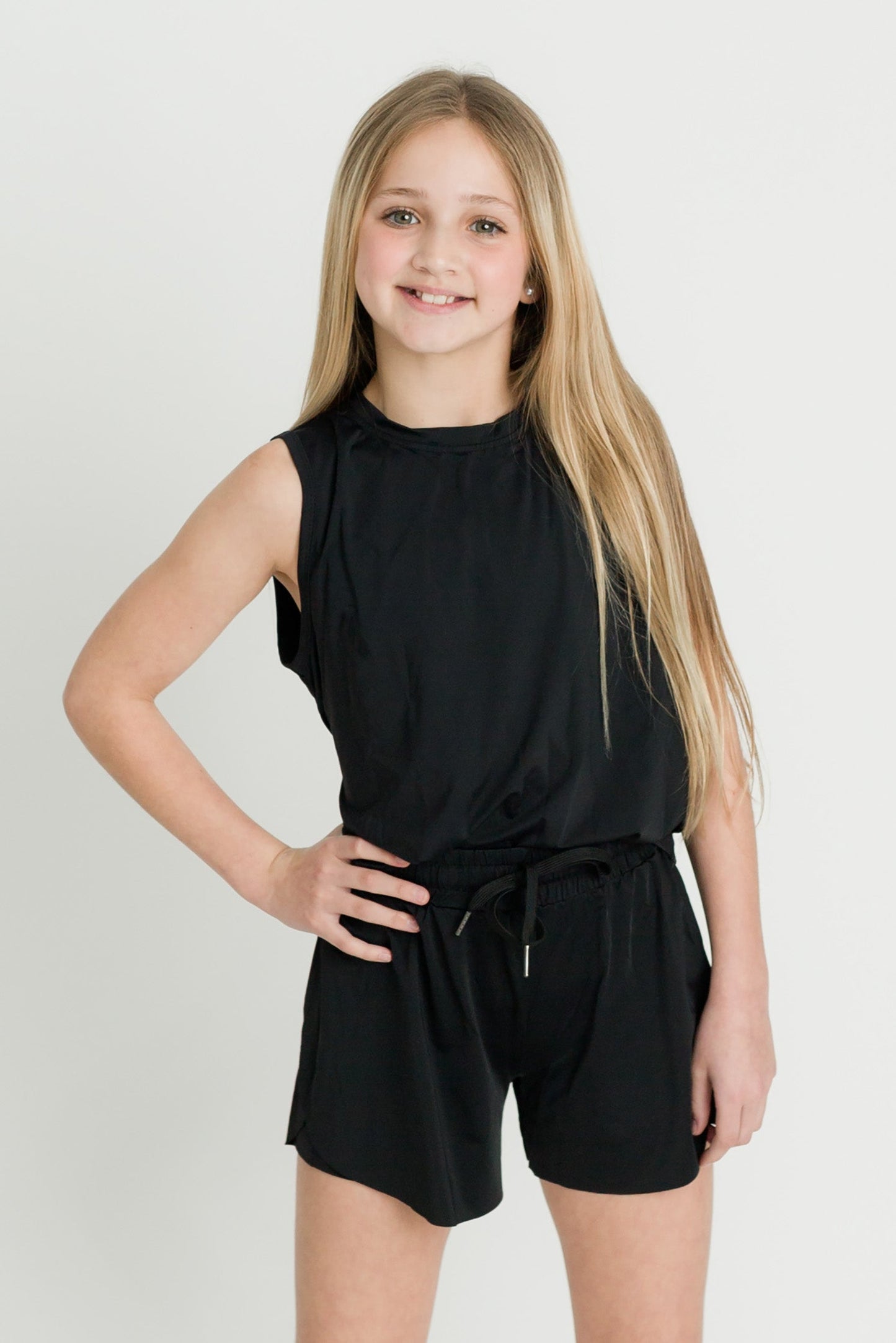 Black high low kid tank worn by smiling girl in casual athletic outfit