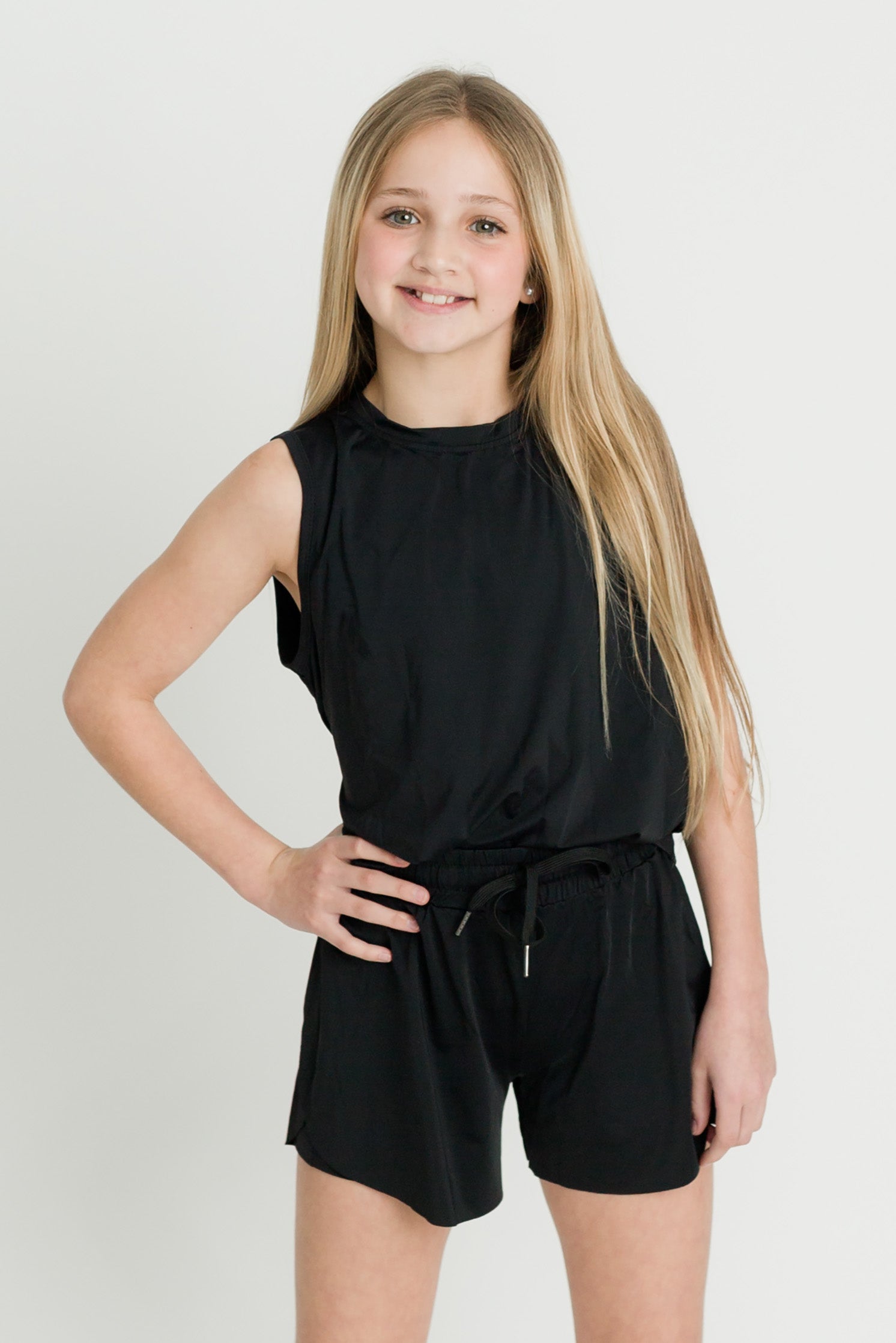 Black high low kid tank worn by smiling girl in casual athletic outfit