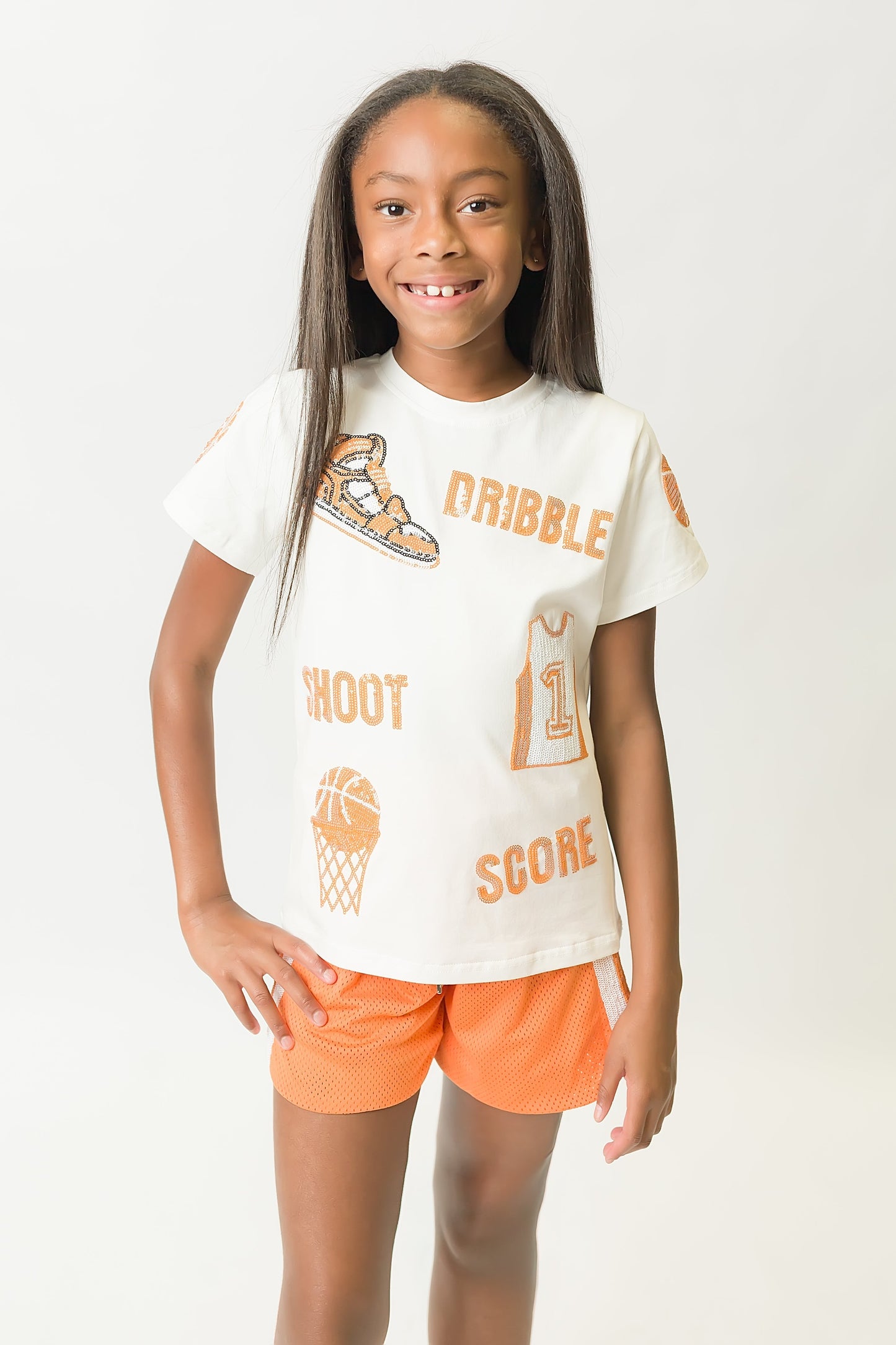 Girl wearing orange basketball shirt and shorts with basketball-themed graphics