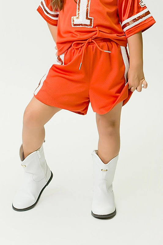 Burnt orange and white sequin shorts with drawstring waist worn with white boots
