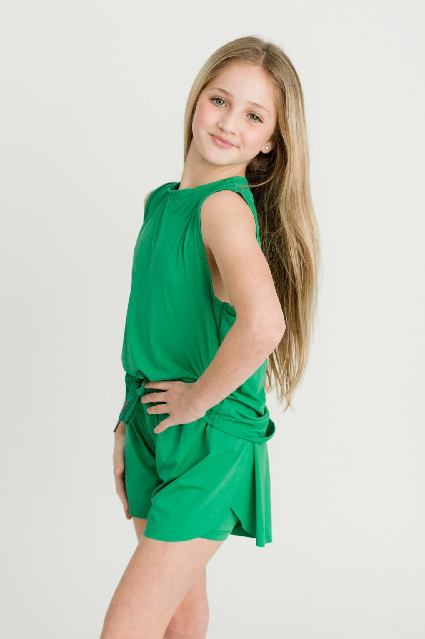 Girl wearing green high low kid tank and matching shorts standing sideways