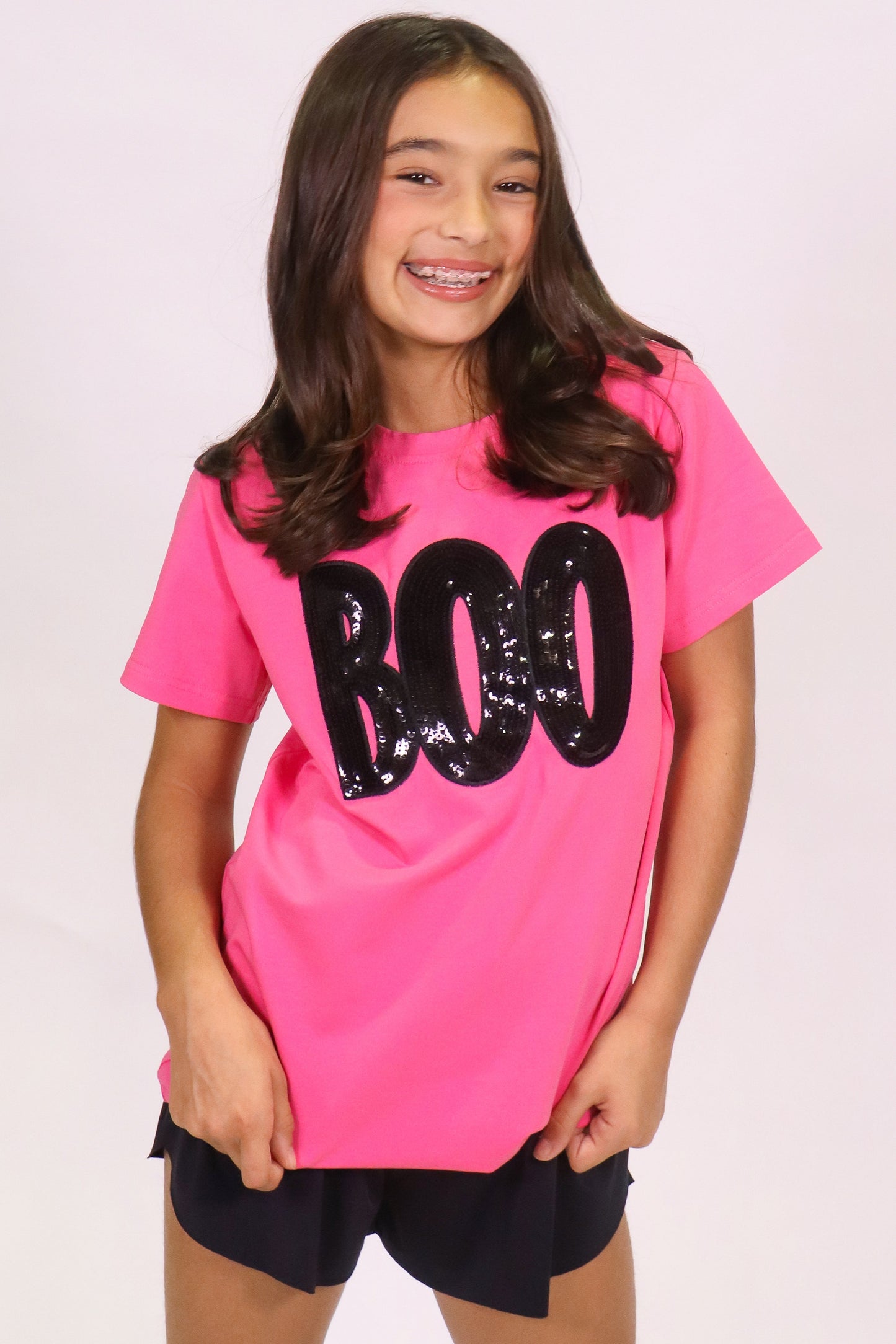 Girl wearing a hot pink Boo shirt with black sequin lettering on Halloween