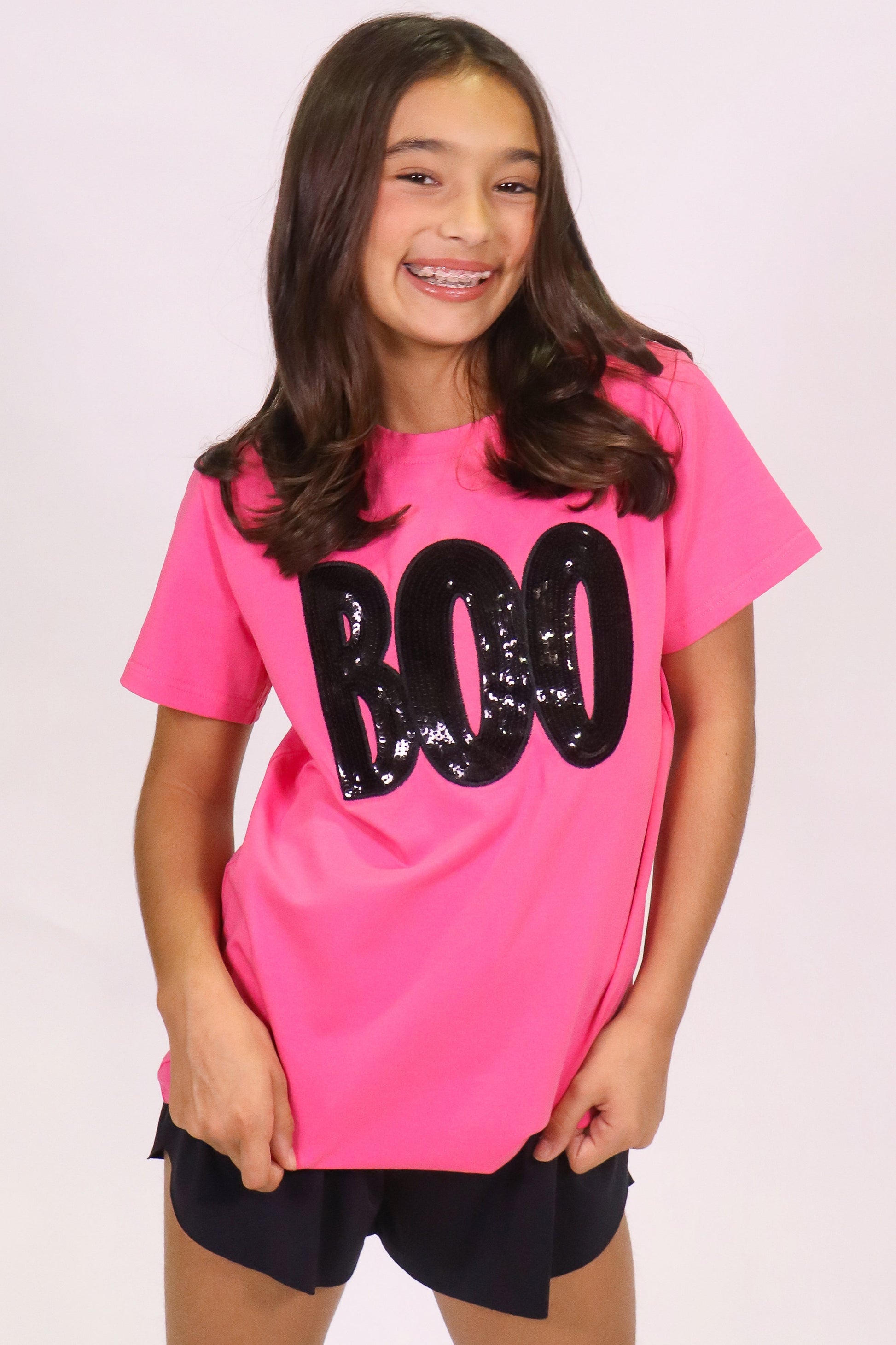Girl wearing a hot pink Boo shirt with black sequin lettering on Halloween