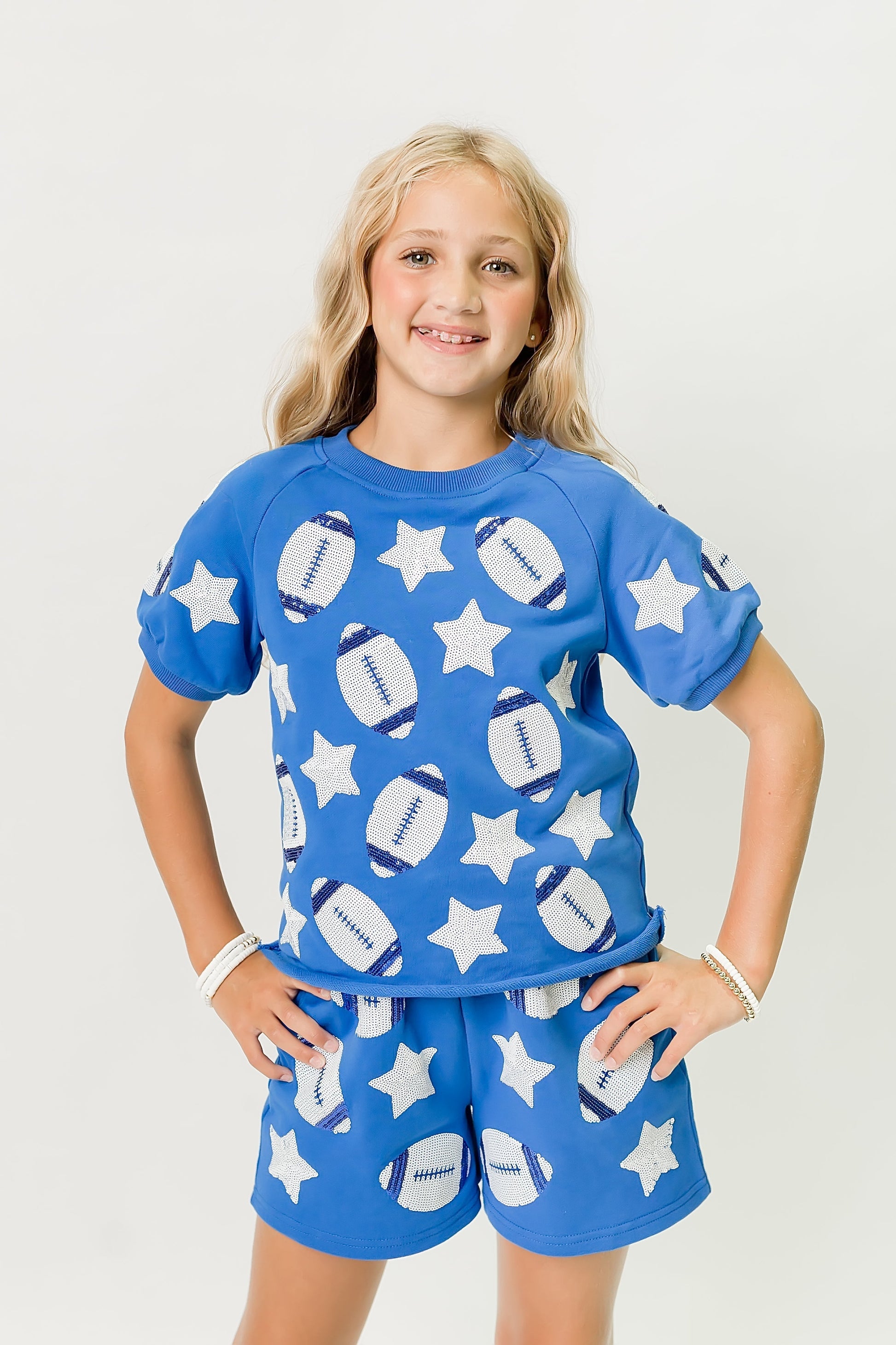 Girl wearing royal blue football top and matching shorts with white stars and footballs designs