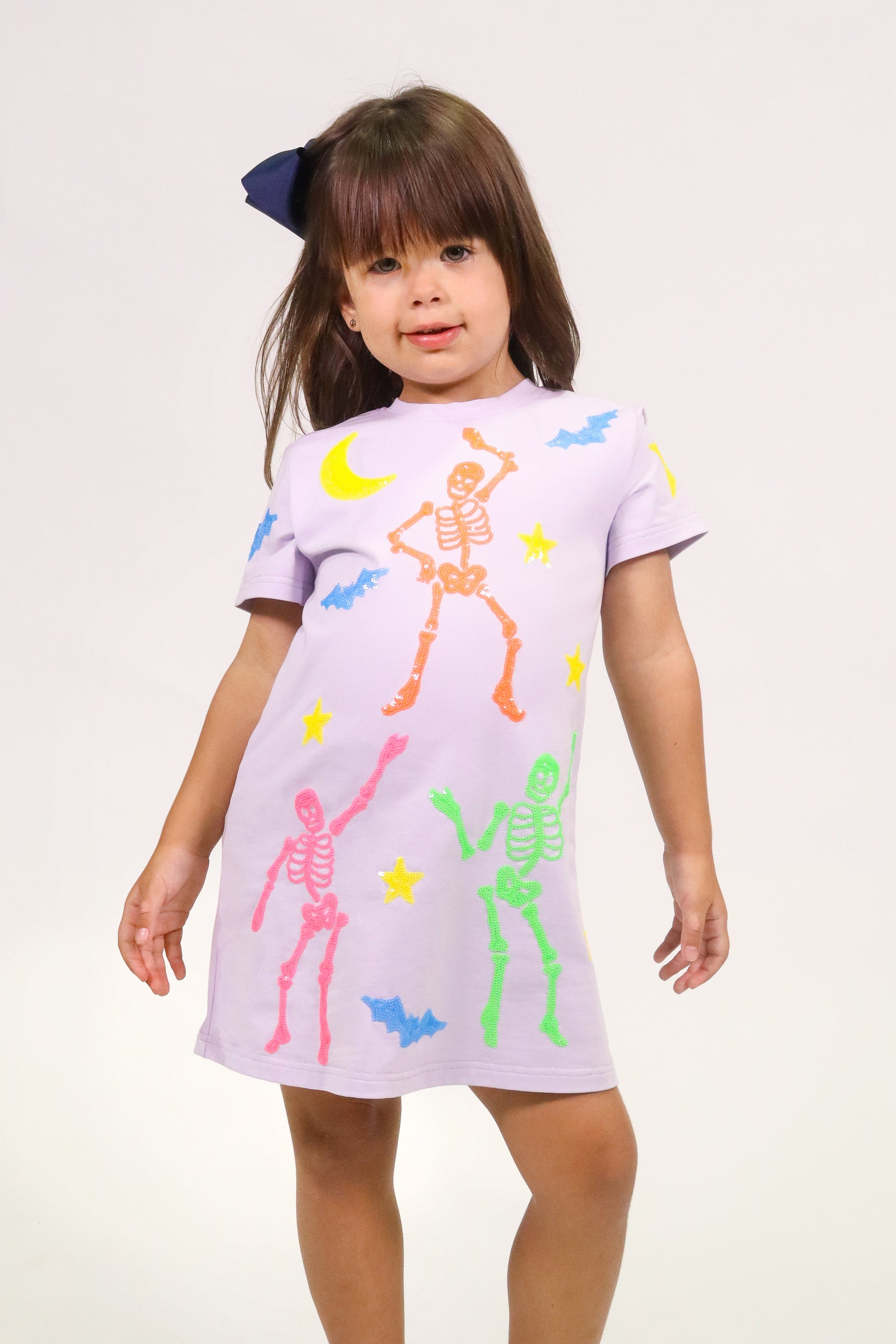 Girl wearing lavender skeleton dress with colorful skeletons and Halloween motifs