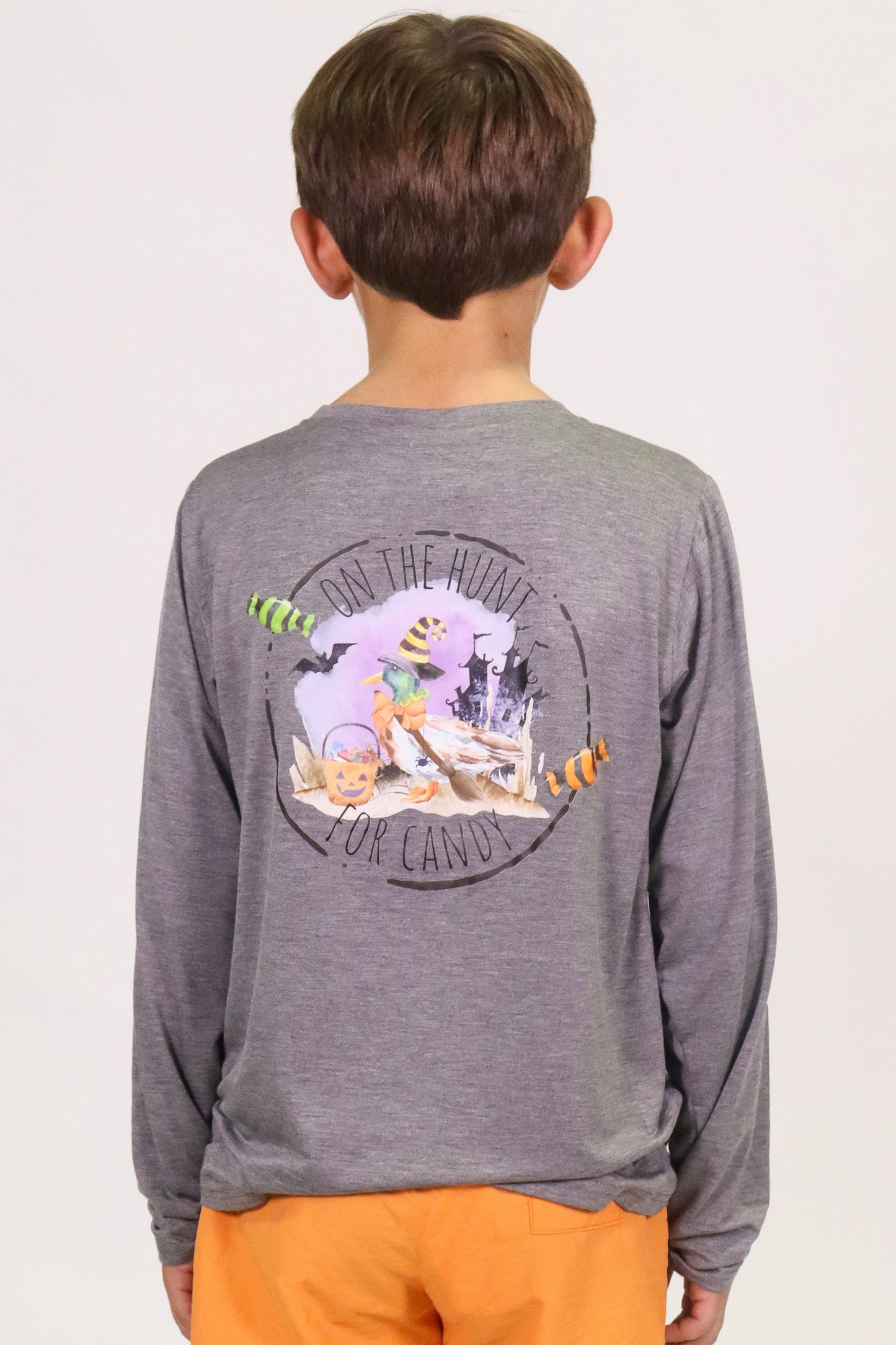 Child wearing grey On the Hunt for Candy long sleeve shirt with Halloween candy design on back