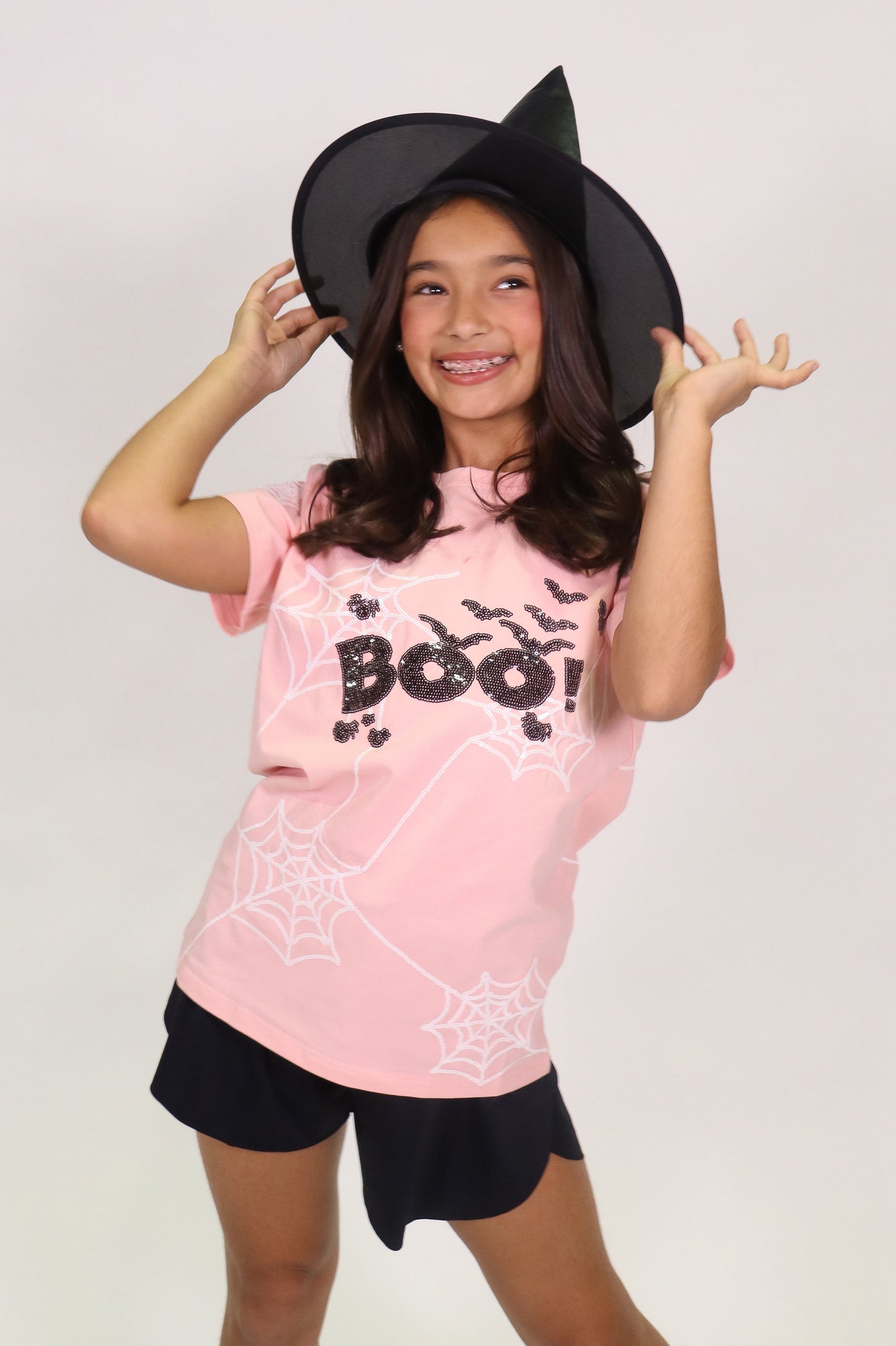 Girl wearing Pink Boo Spider Web Shirt with Halloween hat and black shorts
