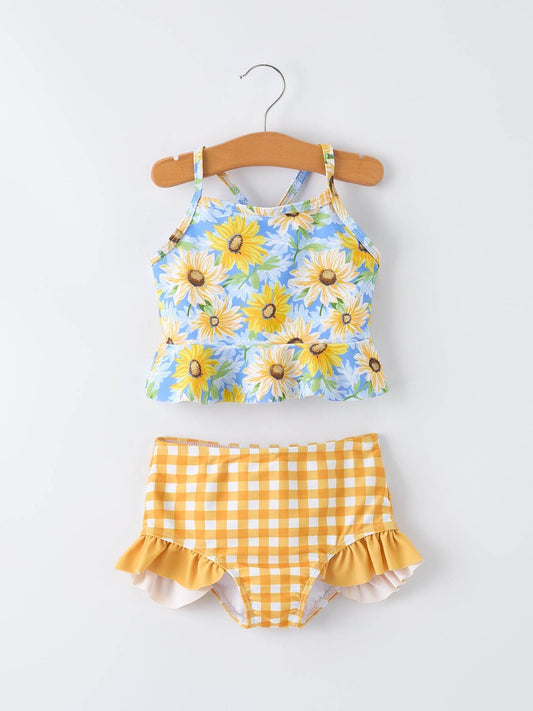 Children's two-piece swimsuit with floral top and checkered shorts on a hanger against a white background.