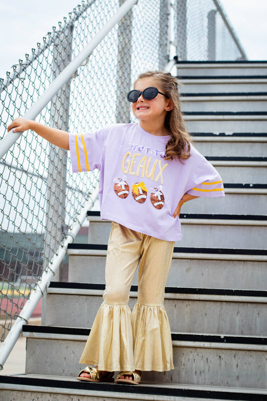 Child wearing SeersuckerJOEY LLC Hot to Geaux sequin tee with oversized fit and gold ruffled pants on outdoor stairs