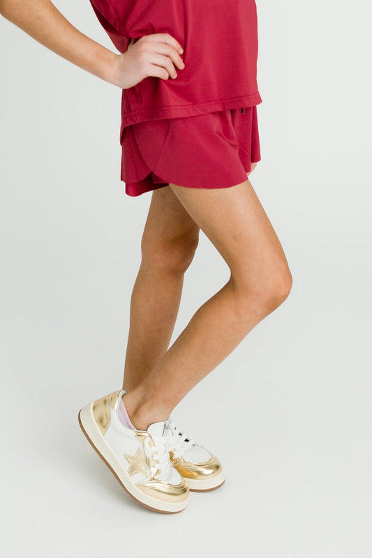Maroon kid butterfly shorts worn with matching top and gold sneakers