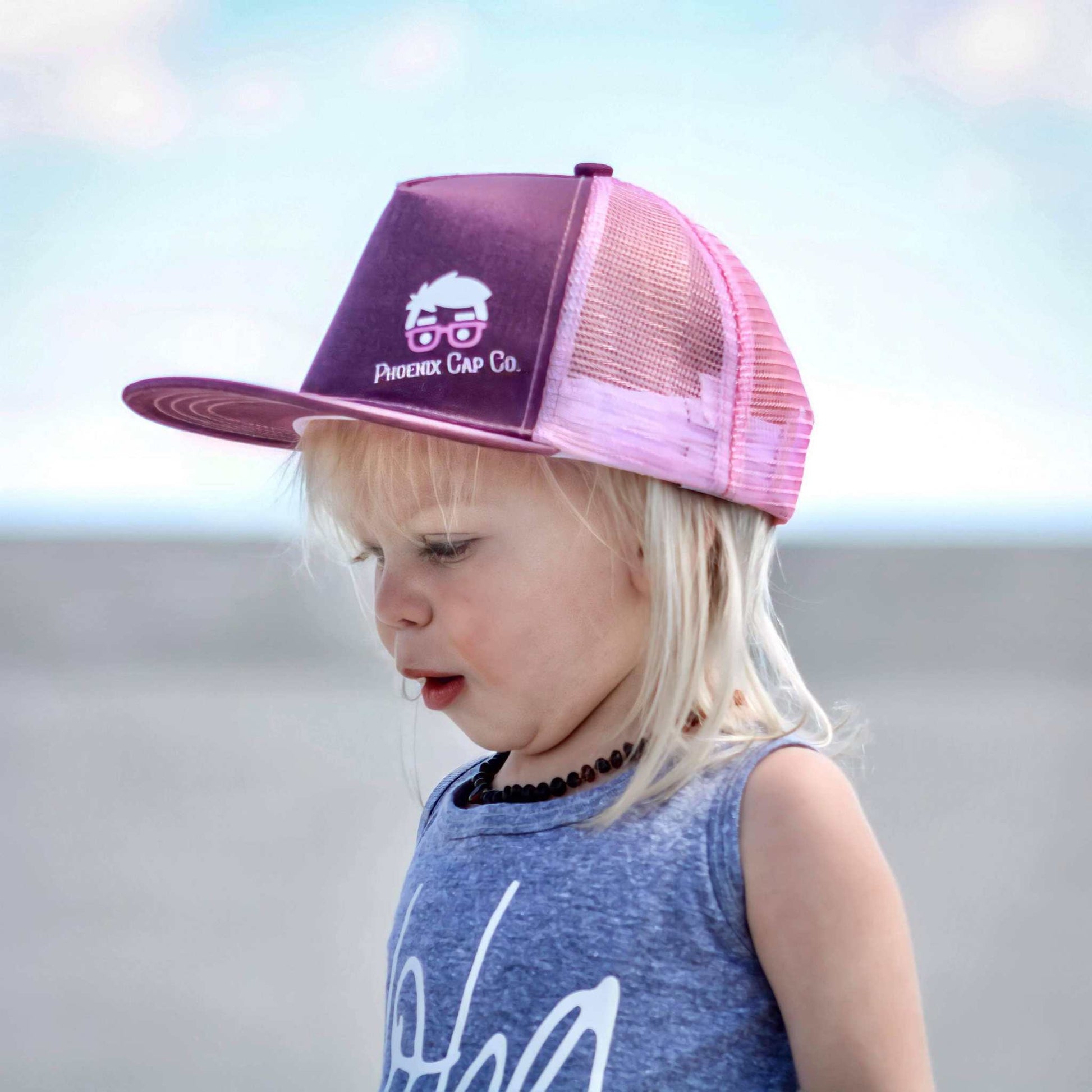 Child wearing Phoenix Cap Co color-changing seahorse trucker hat which shifts from purple to pink when wet.